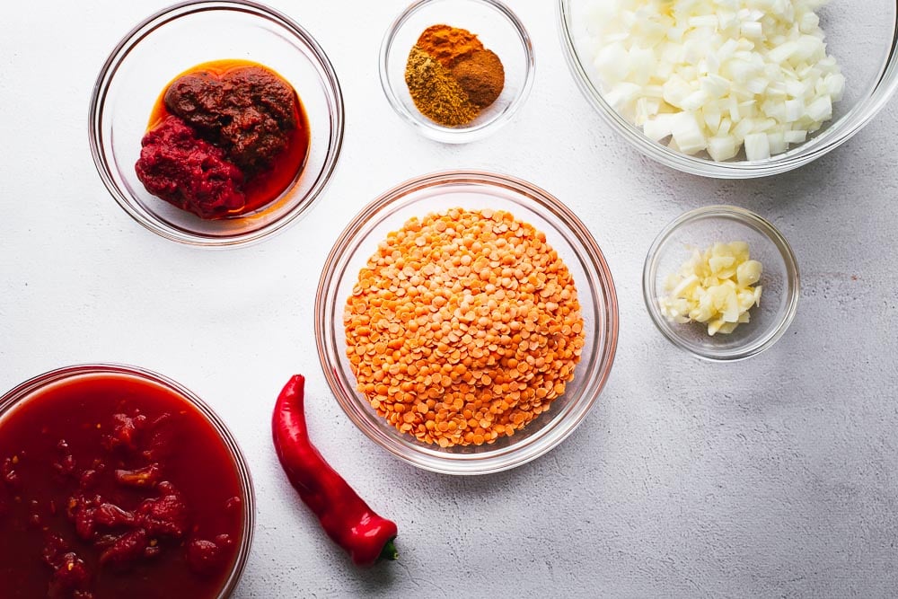 Ingredients for harissa and red lentil soup arranged in glass bowls.