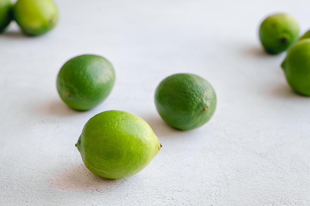 Fresh green limes on a grey concrete backdrop