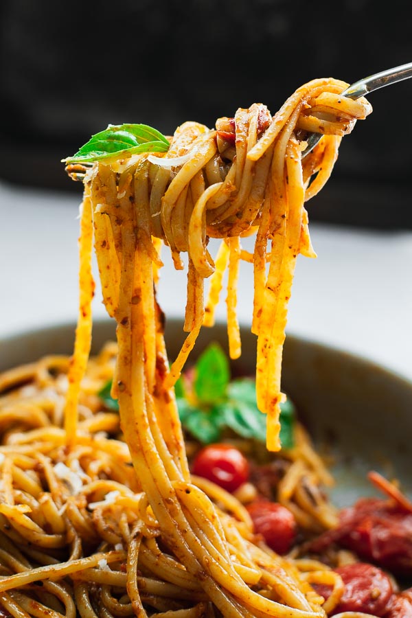 Pasta with harissa tomato sauce on a fork.