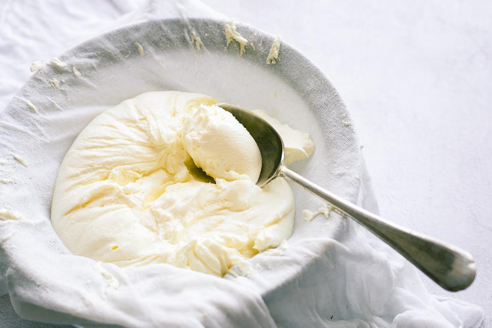 Strained yoghurt cheese (or labneh) in a sieve lined with muslin cloth.