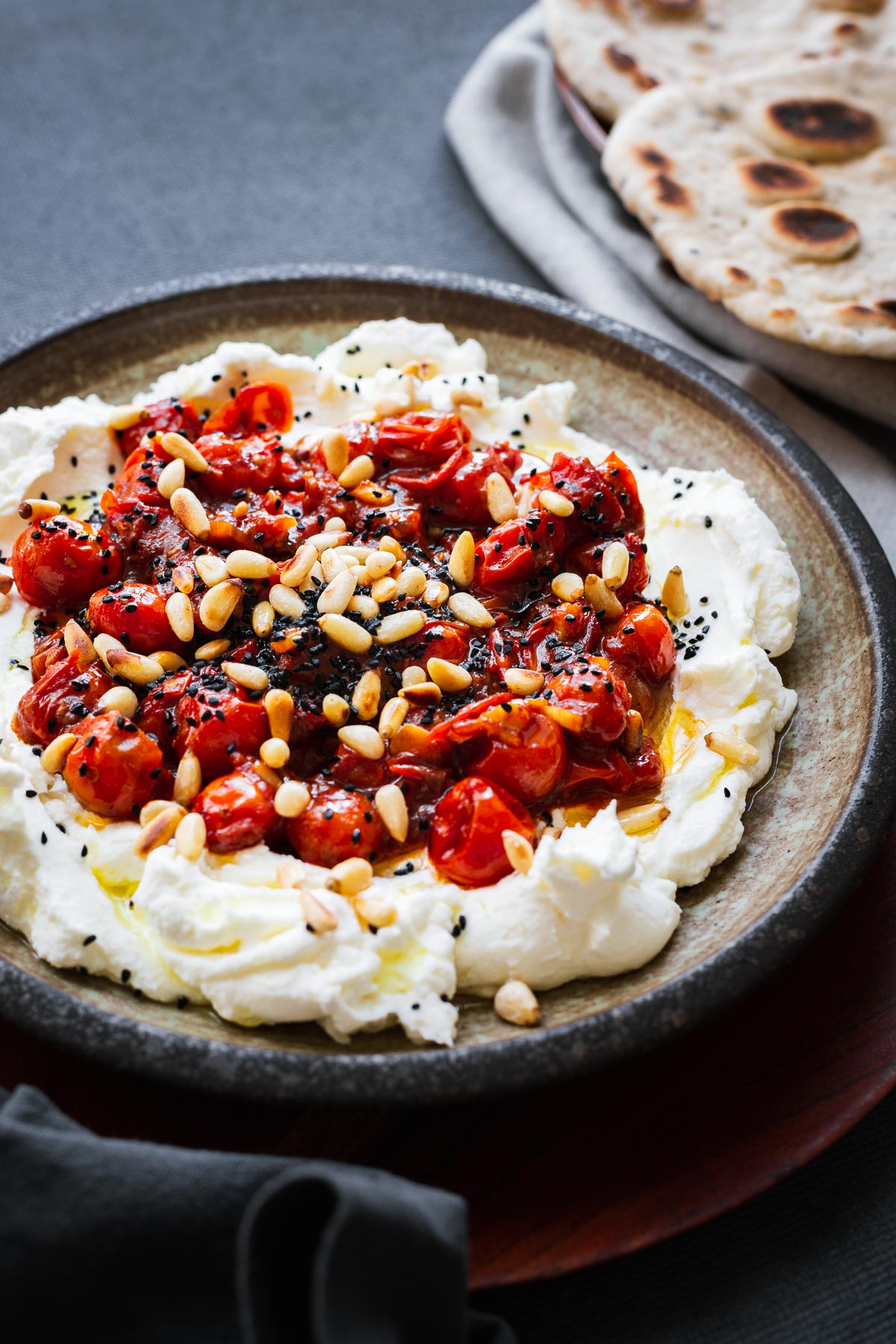 Spicy harissa tomatoes on homemade labneh with flatbreads to enjoy as an appetiser.