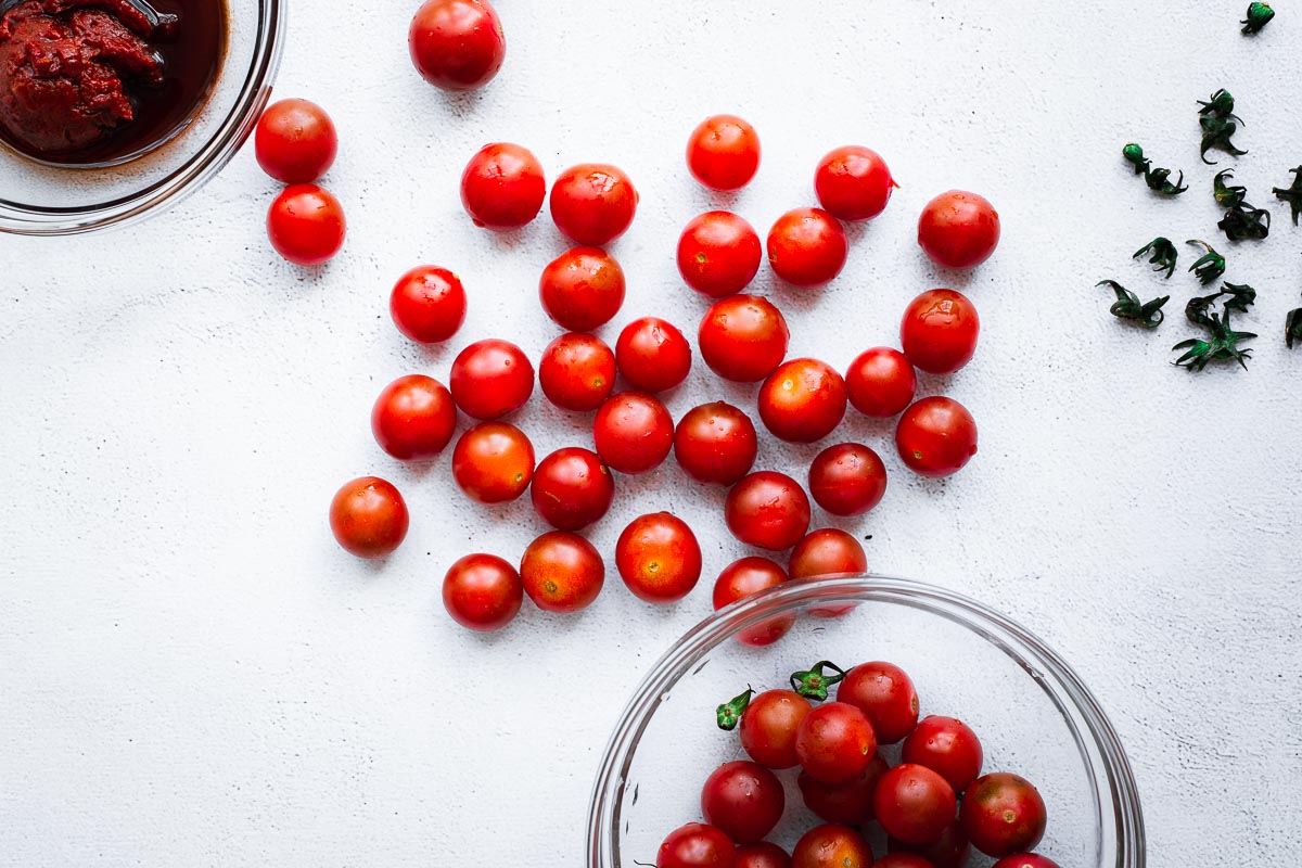 Bright red cherry tomatoes on a concrete surface.