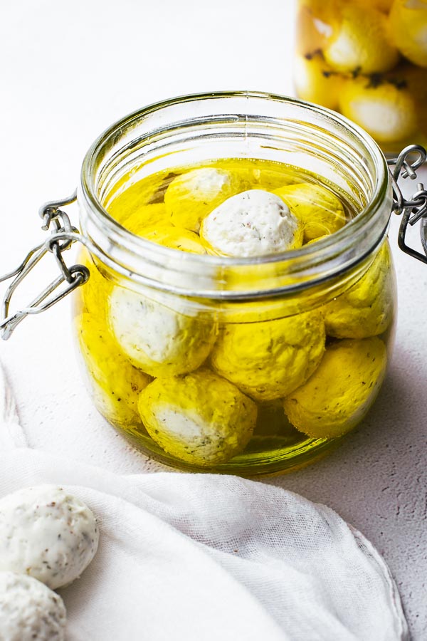 Garlic and herb labneh balls in a jar of olive oil.