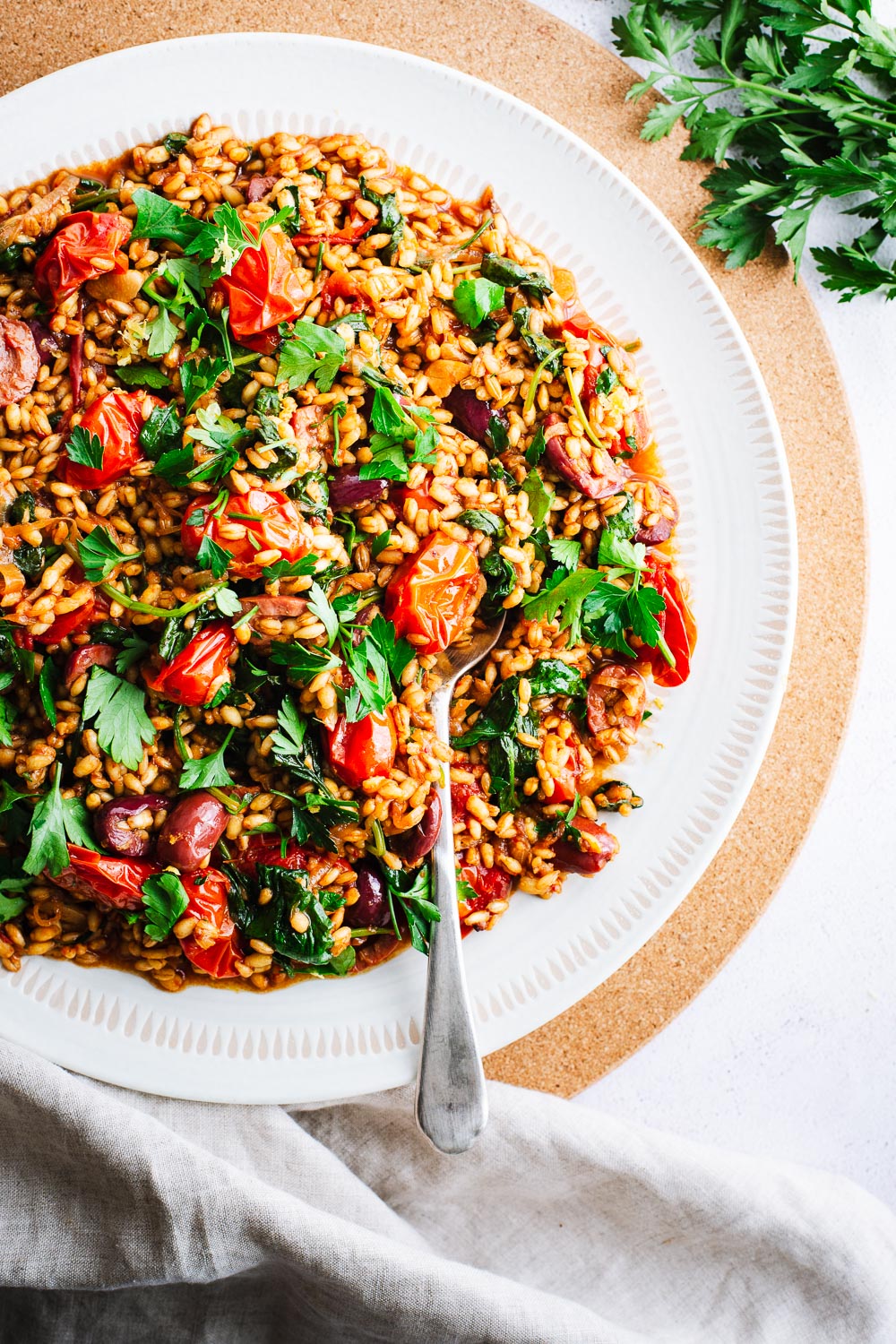 Healthy barley pilaf with rose harissa, tomatoes, olives and baby spinach.