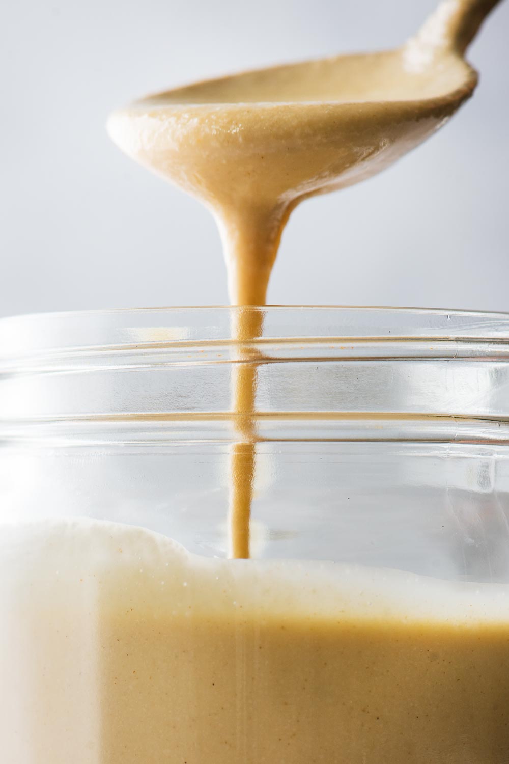 A close-up shot of thin and pourable homemade tahini that has added olive oil.