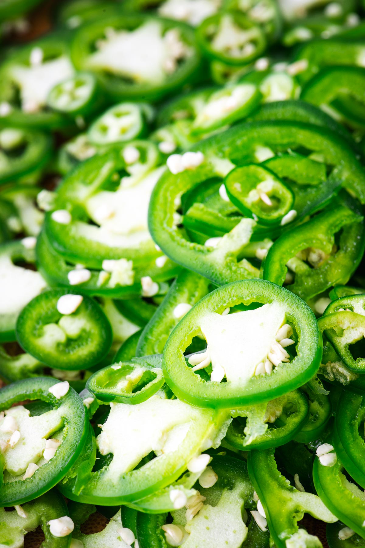 A close-up of thinly sliced mixed green chillies, such as jalapeños, serrano peppers and green finger chillies.