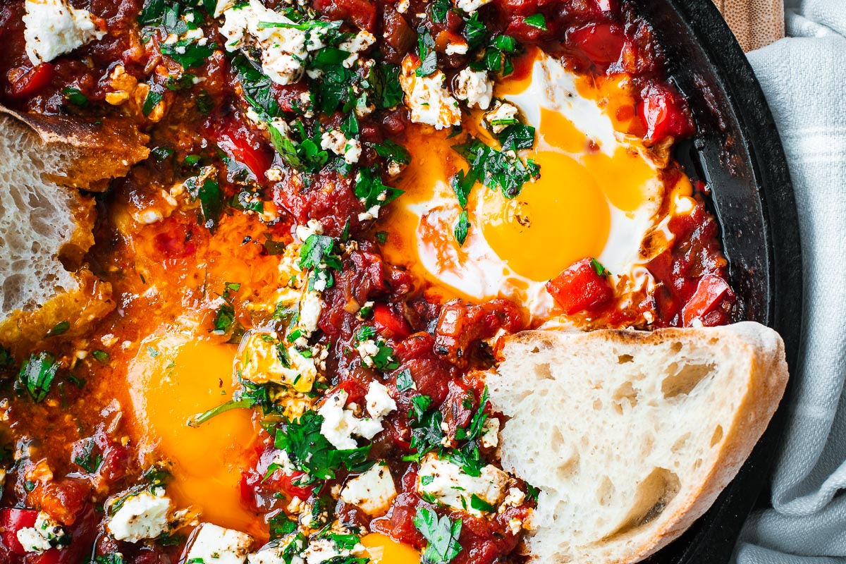 A close-up of shakshuka with very soft egg yolks in a cast iron skillet viewed from above.