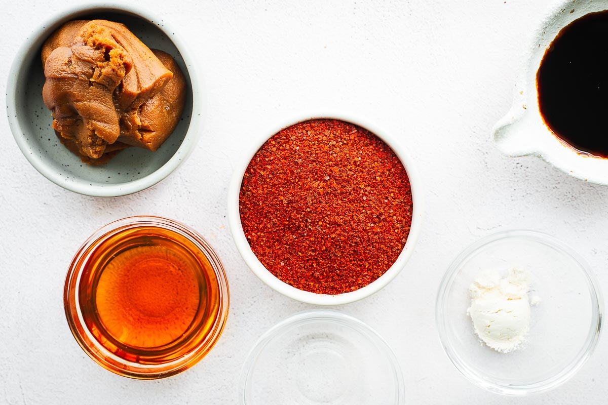 Small bowls with miso paste, gochugaru, soy sauce, maple syrup, onion powder and rice vinegar.