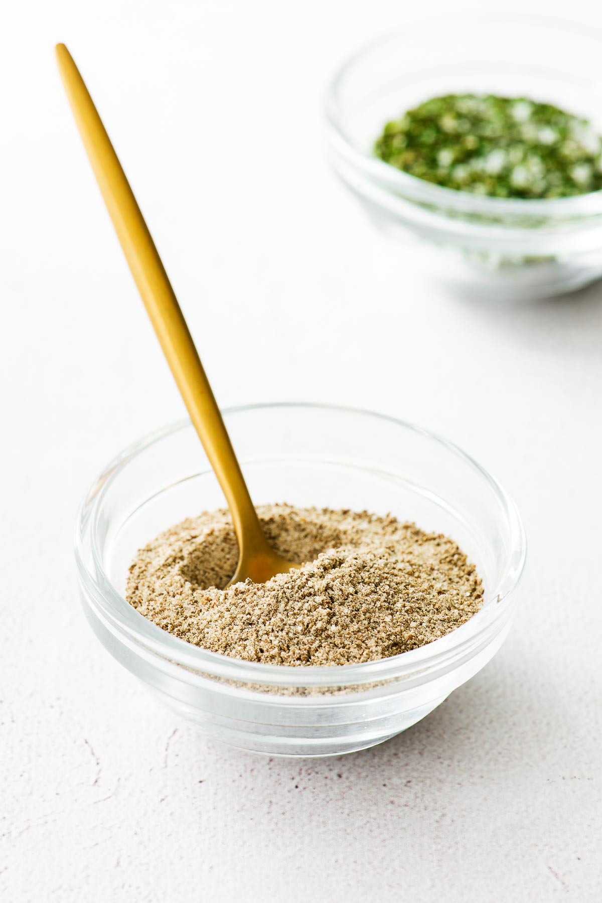 Celery salt substitute made from ground celery seeds and salt in a glass bowl with a golden spoon.