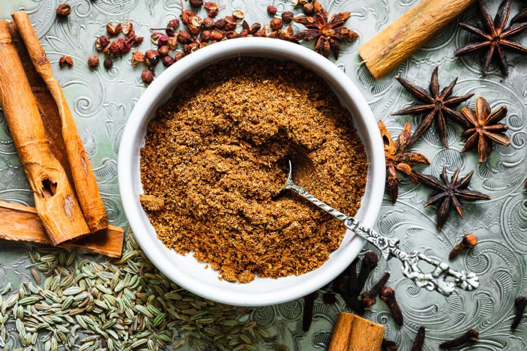Chinese five-spice powder in a small bowl surrounded by spices viewed from above.