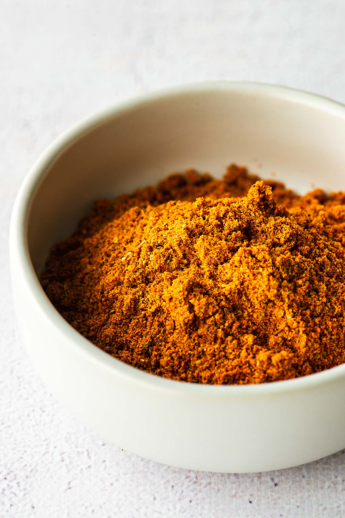 Close-up of homemade Old Bay seasoning substitute in a small white bowl.