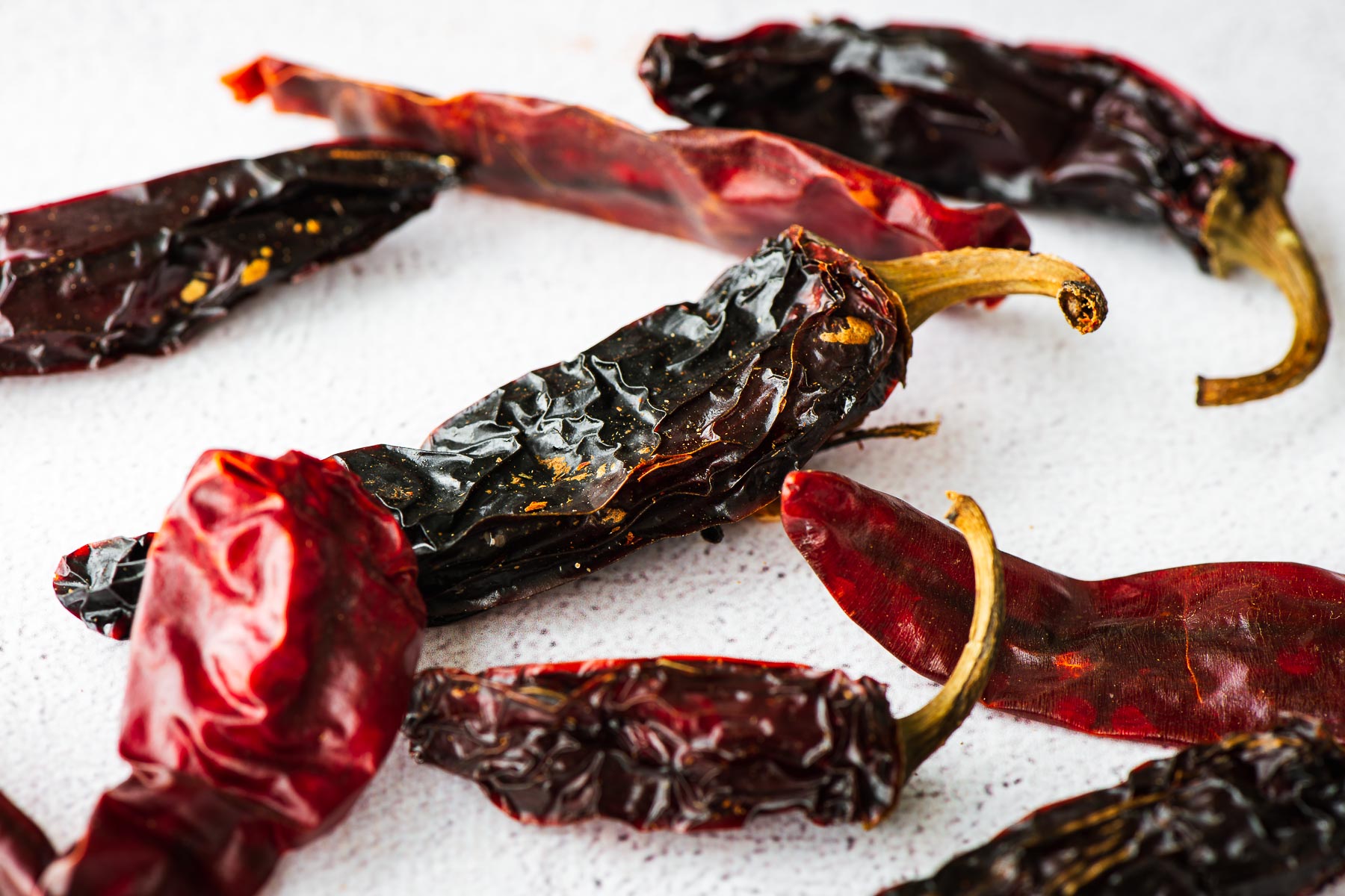 A close-up of dried Jalapeño peppers and red chillies on a concrete background.