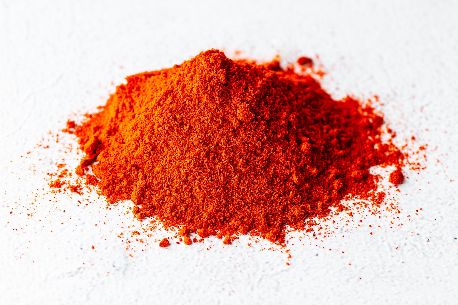 Close-up of Kashmiri chilli powder in a small heap on a concrete background.