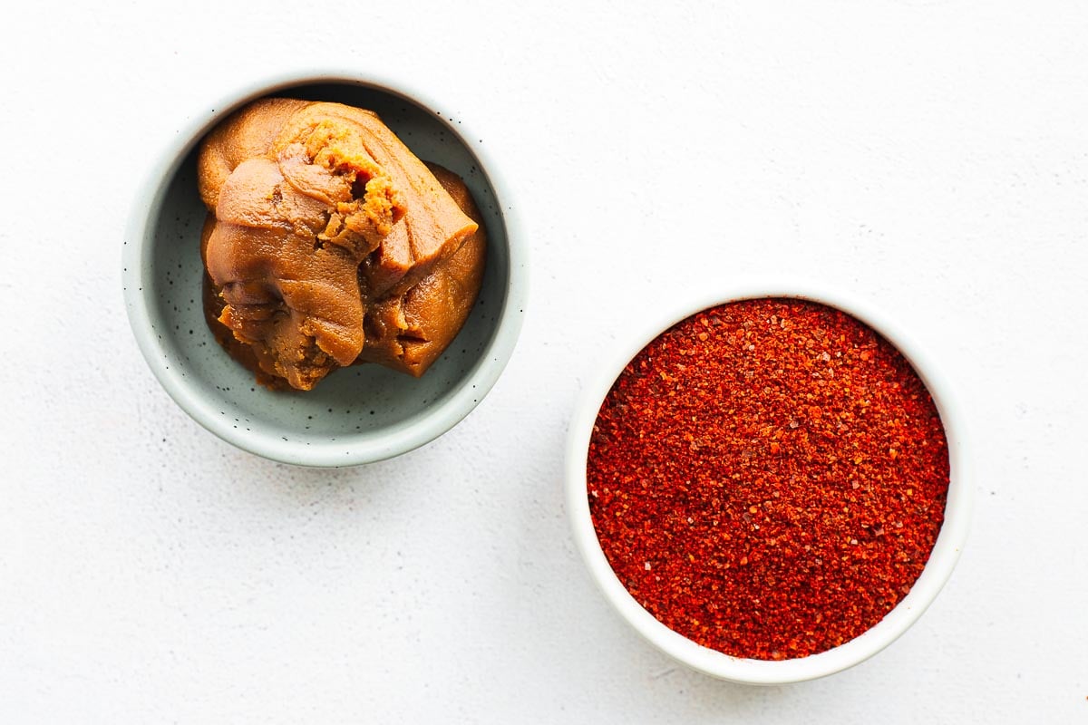 Miso paste and gochugaru in small bowls viewed from above.