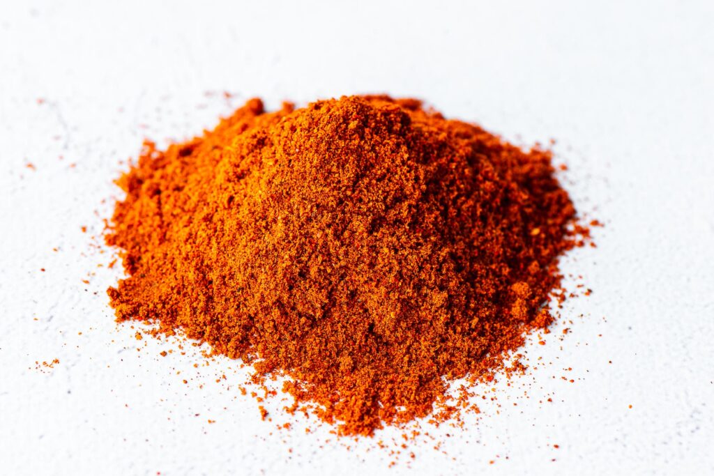 A close-up of paprika powder in a small heap on a concrete background.
