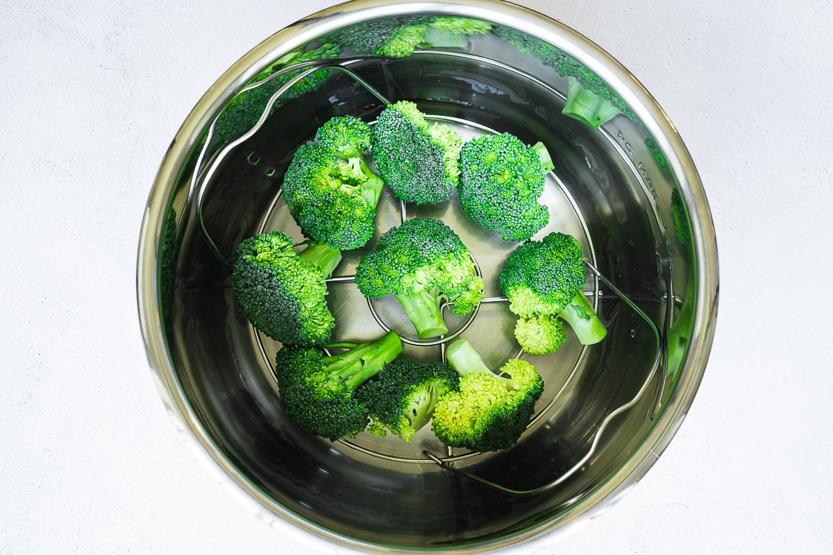 Large broccoli florets layered in on a metal trivet in the instant pot.