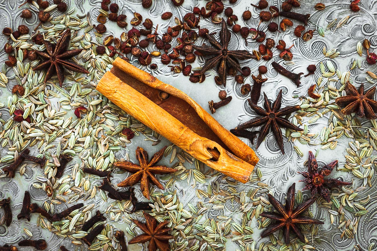 The main ingredients of Chinese five spice viewed from above, including Chinese cinnamon, star anise pods, fennel seeds, Sichuan peppercorns and cloves.