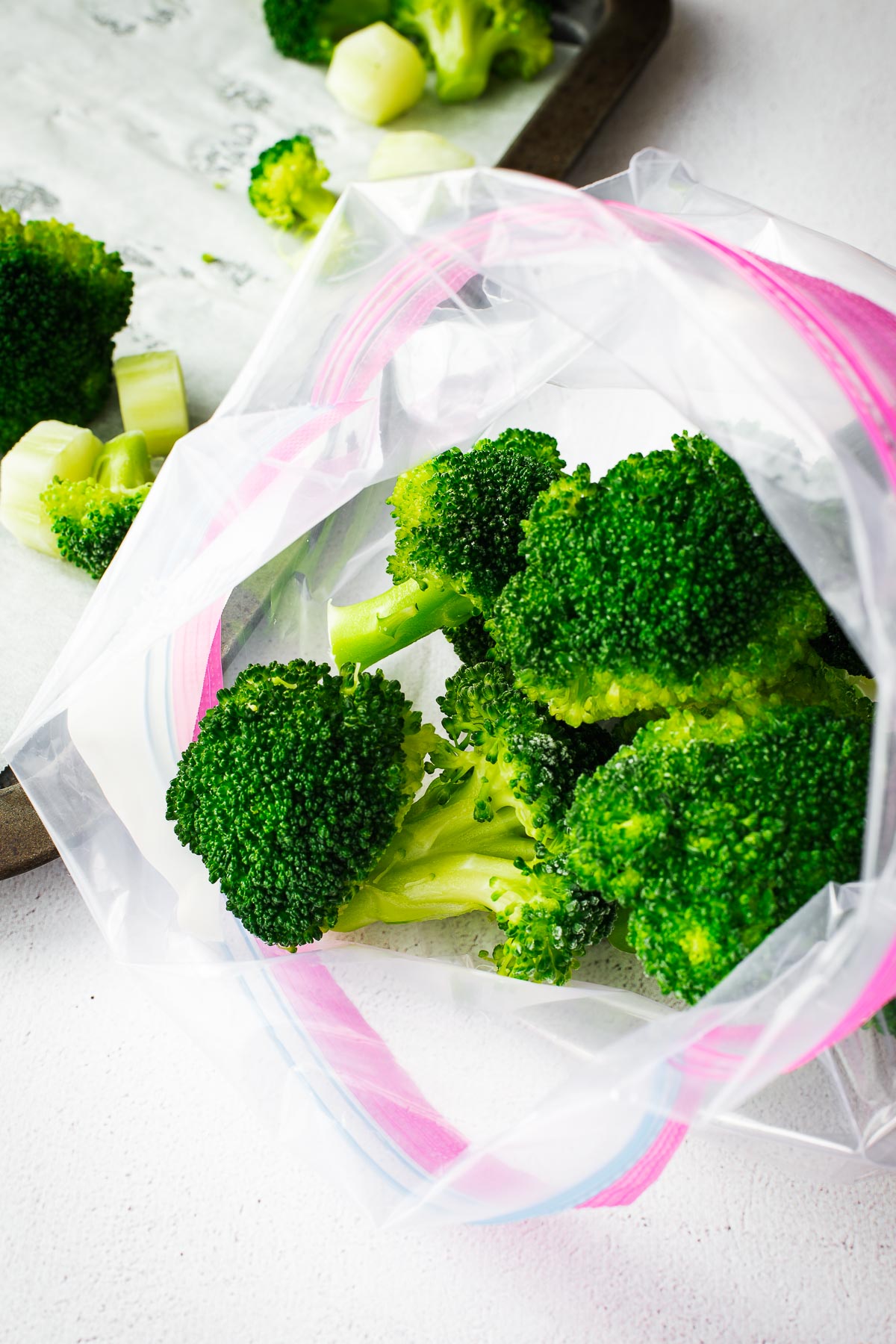Placing flash frozen broccoli florets in a clean freezer bag.