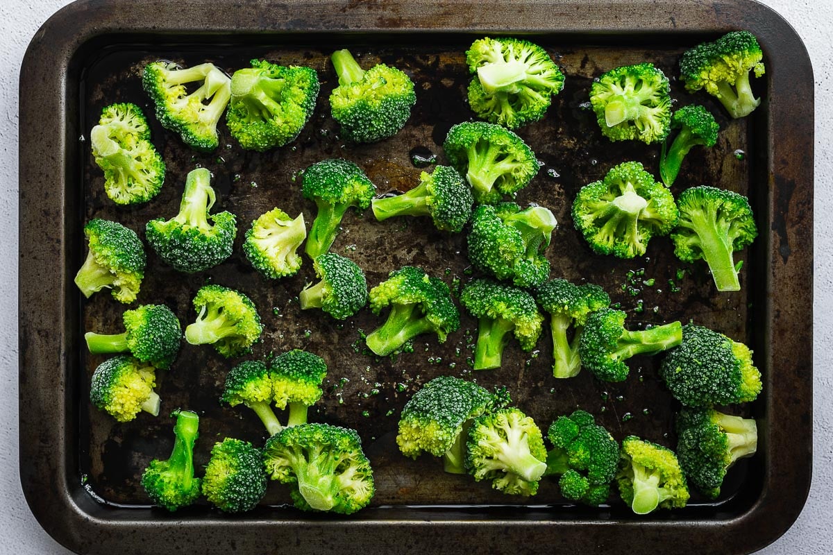 Frozen broccoli on a preheated baking tray with olive oil.