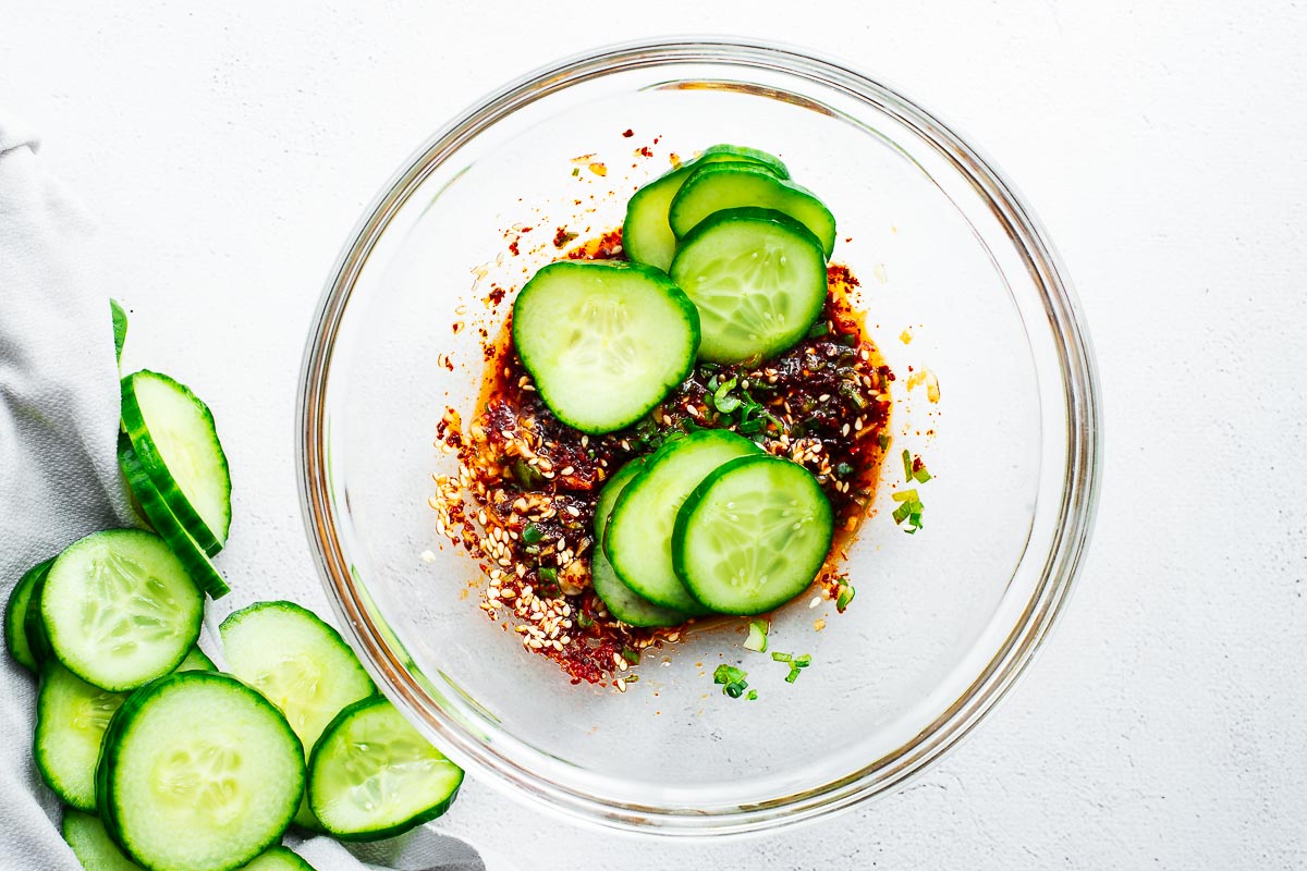 Seasoned cucumbers in a bowl with a spicy gochugaru dressing, viewed from above.