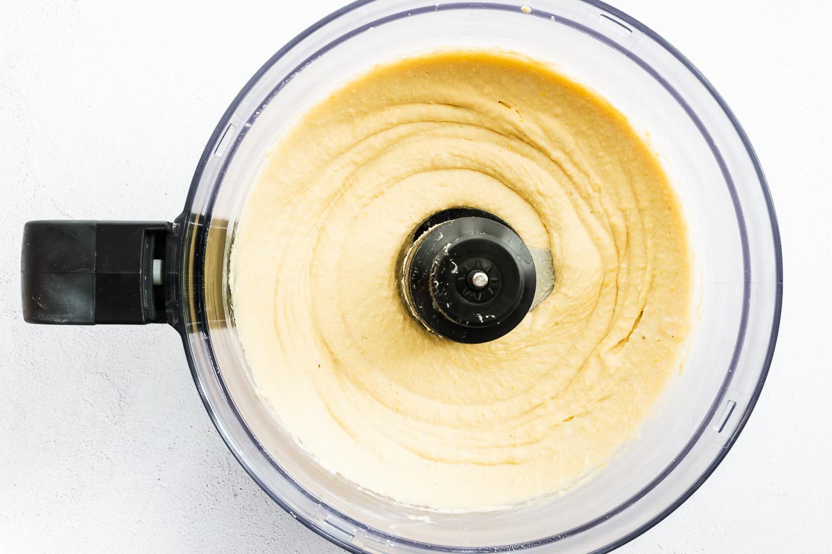 Smooth hummus in a food processor viewed from above.