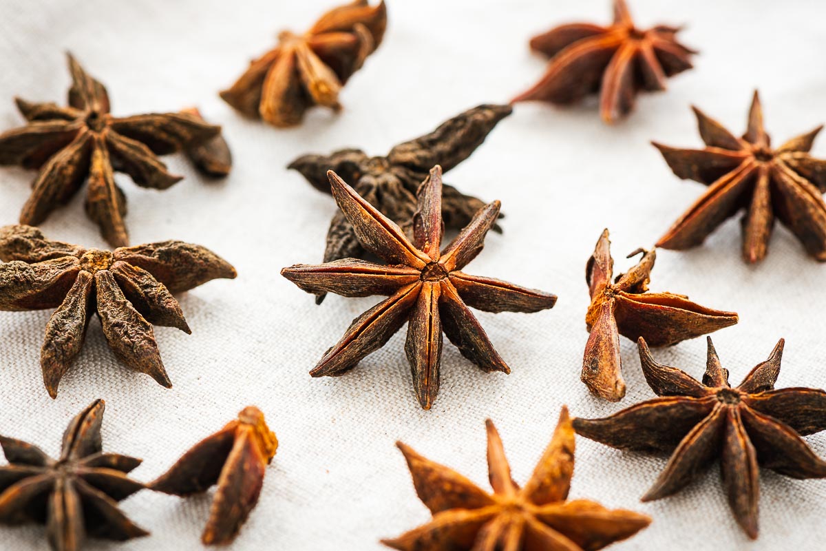 Close-up of whole star anise pods on a neutral fabric.