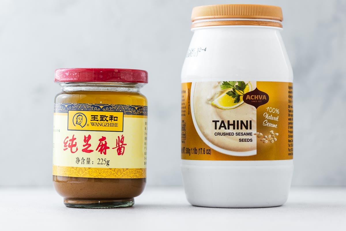 A glass jar of Chinese sesame paste next to a plastic jar of tahini.