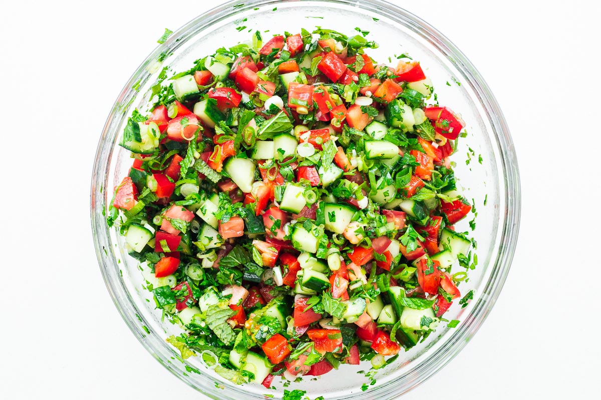A mixed chopped salad in a glass bowl viewed from above.