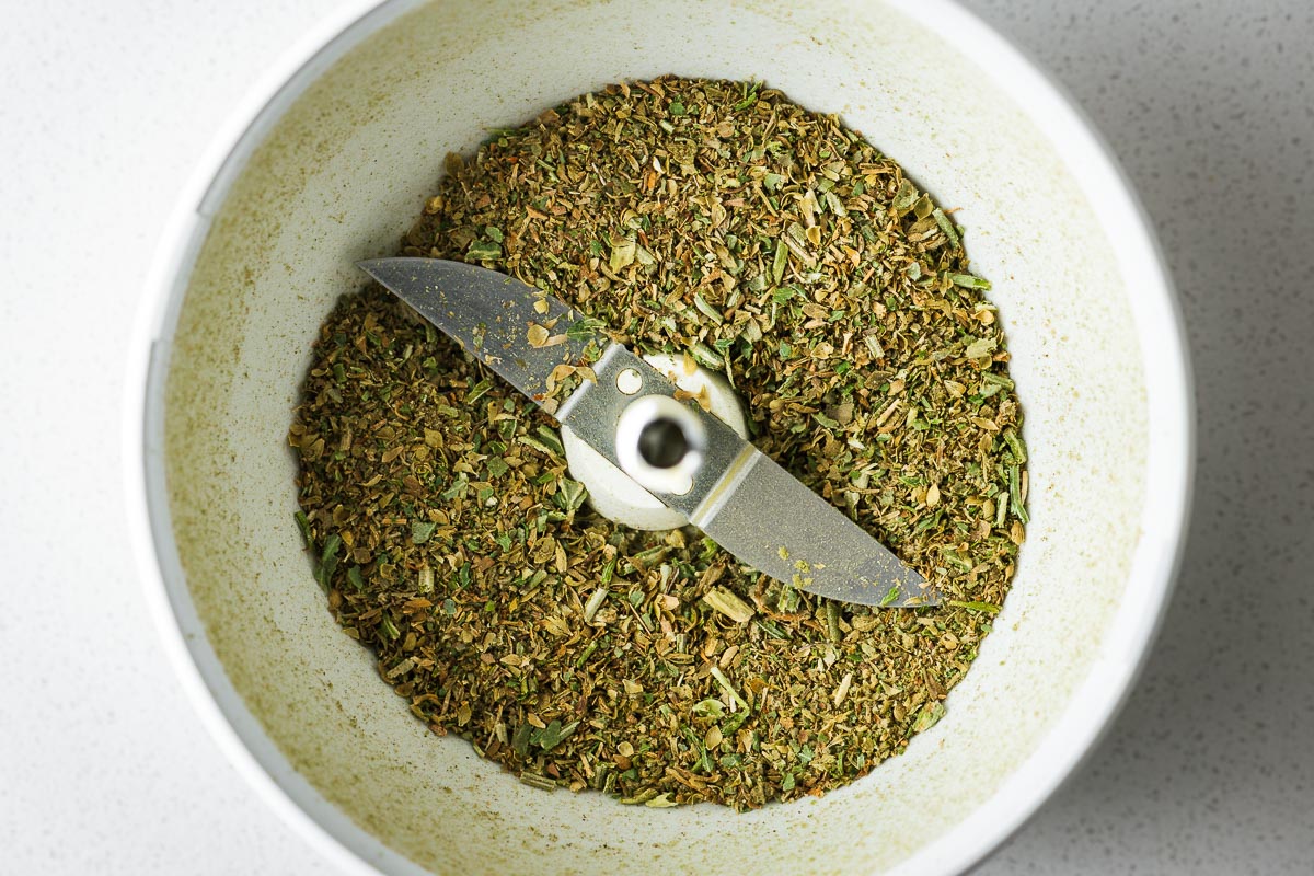 Top down view of ground Italian seasoning in a spice grinder.