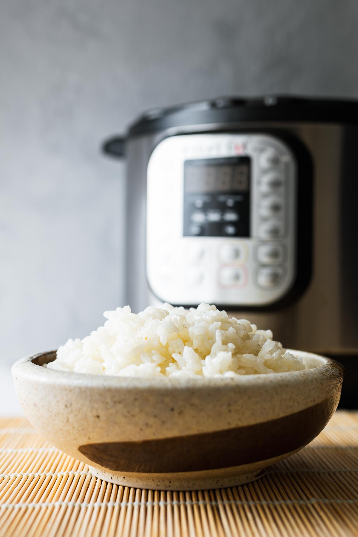 A bowl of fluffy white sushi rice with an instant pot in the background.