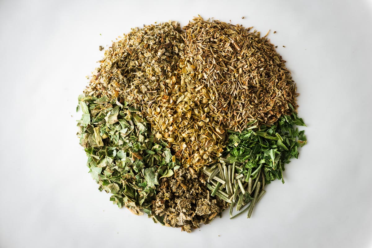 Close-up of ingredients for homemade Italian seasoning on a plate.