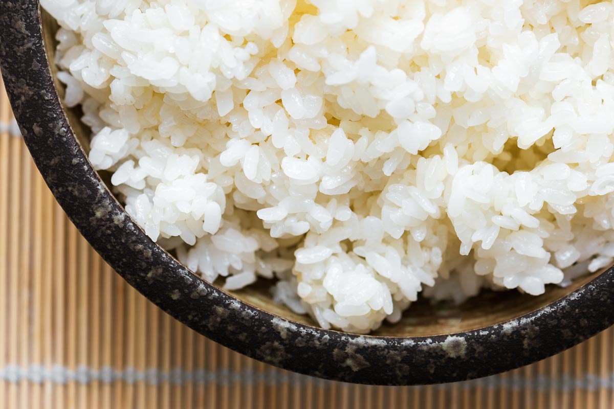 A close-up shot of sticky yet fluffy sushi rice in a brown Japanese bowl.
