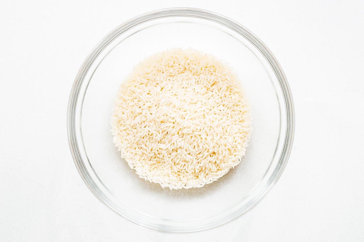 Uncooked jasmine rice in a glass bowl viewed from above.