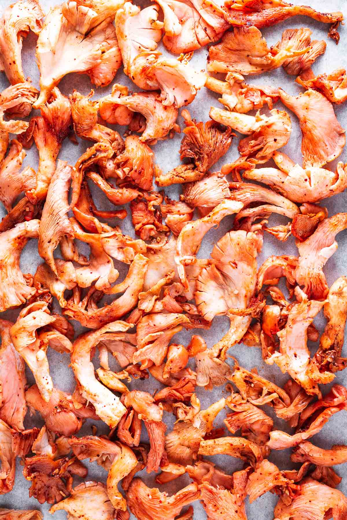 Marinated pink oyster mushrooms on a baking tray viewed from above.