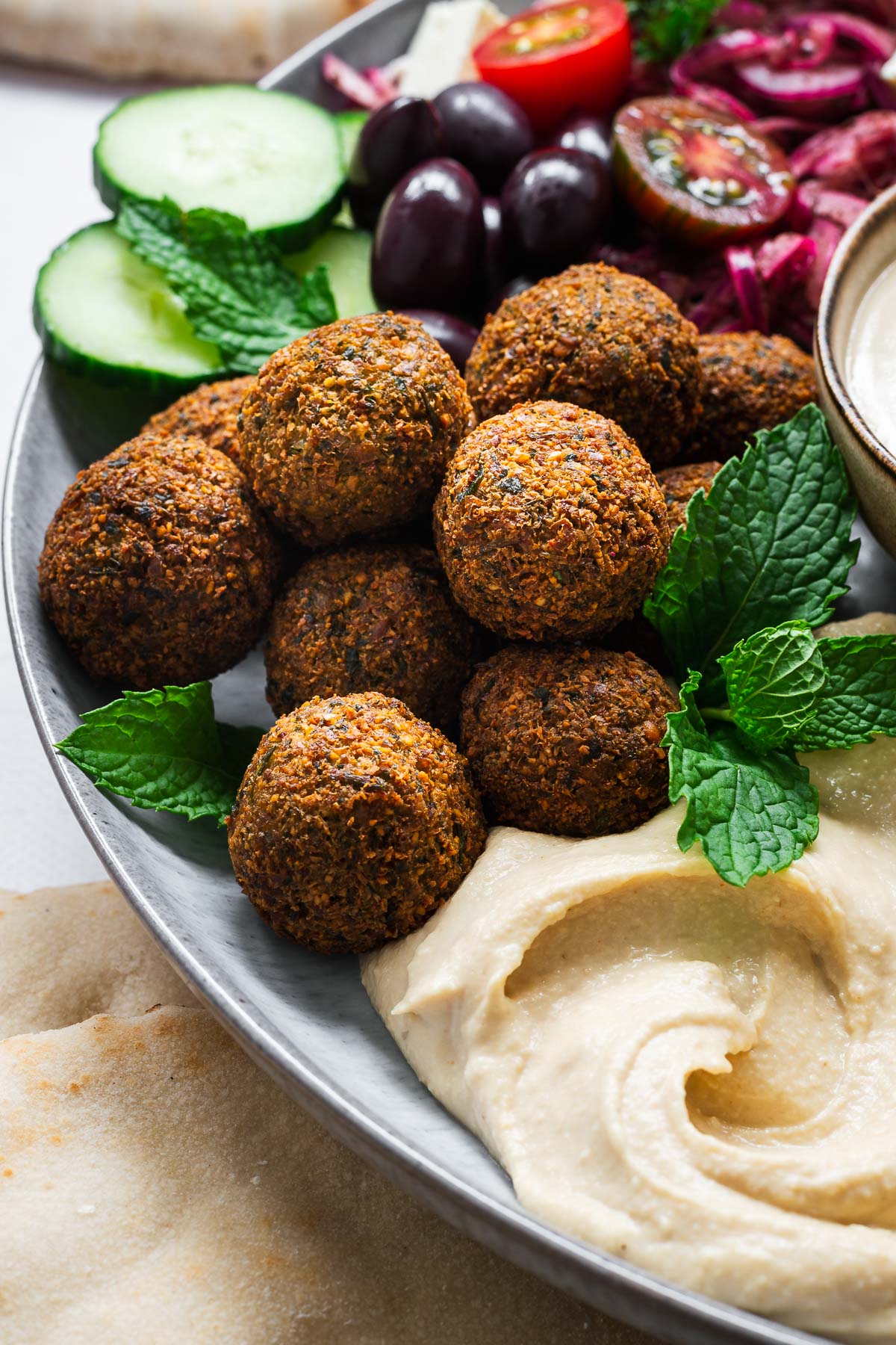 Crispy Middle Eastern falafel balls with hummus, tahini sauce and fresh salad in a large bowl.