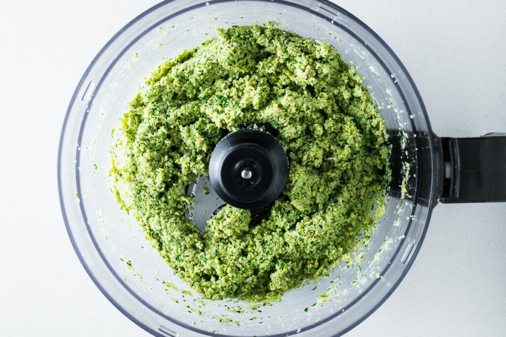 Herbed falafel mixture in the bowl of a food processor.