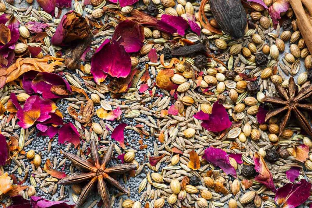 Close-up of toasted garam masala spices, including star anise, rose petals, black pepper, cumin, coriander and cardamom.