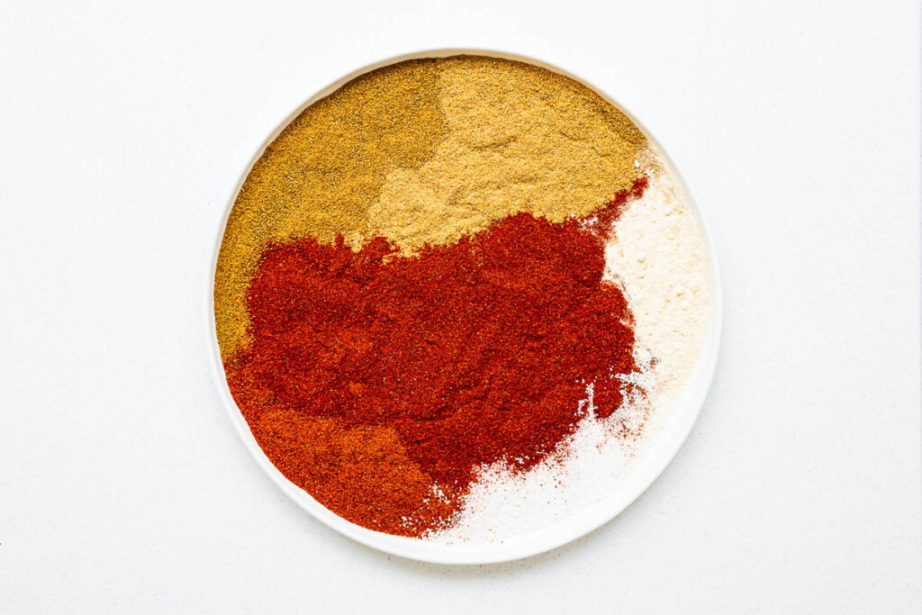 A small plate, viewed from above, with the different spices that goes into a harissa spice blend.