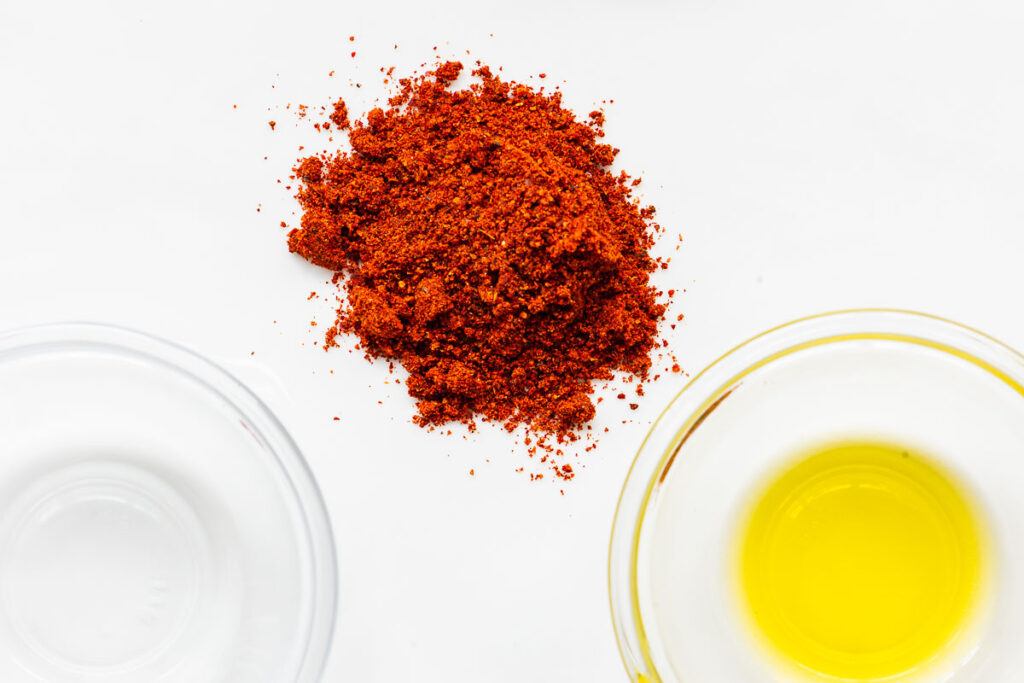 A small pile of harissa powder and small bowls of water and olive oil.