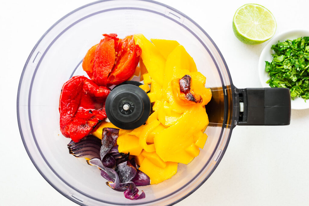 Ingredients for roasted mango habanero salsa in a food processor.