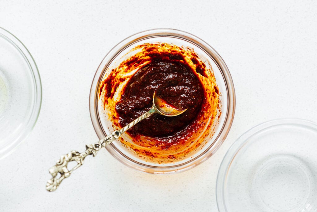 Harissa paste made by rehydrating harissa powder next to empty glass bowls.