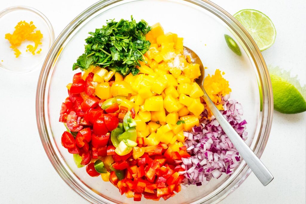 Diced ingredients for fresh mango habanero salsa in a glass bowl.