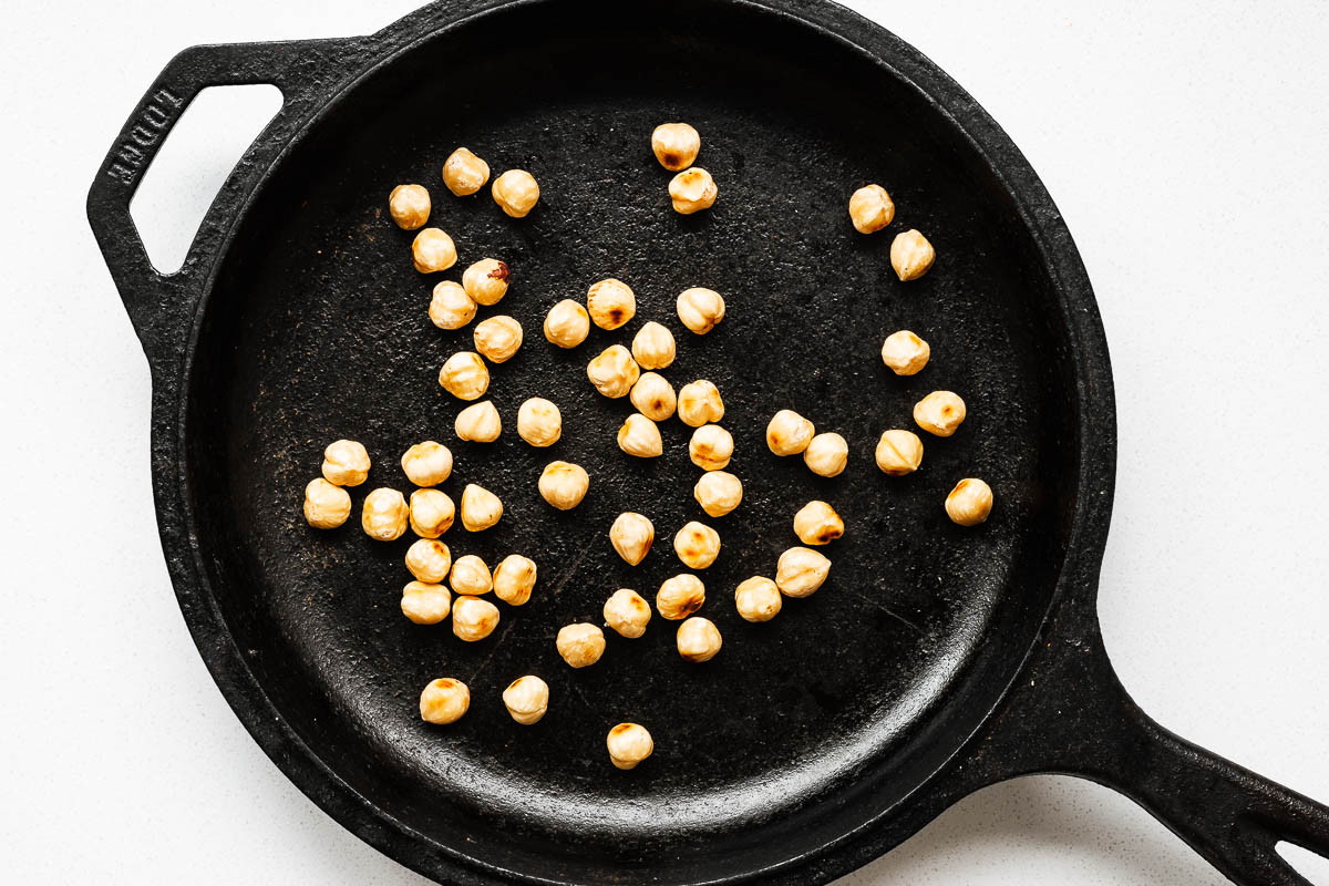 A cast-iron skillet with toasted hazelnuts.