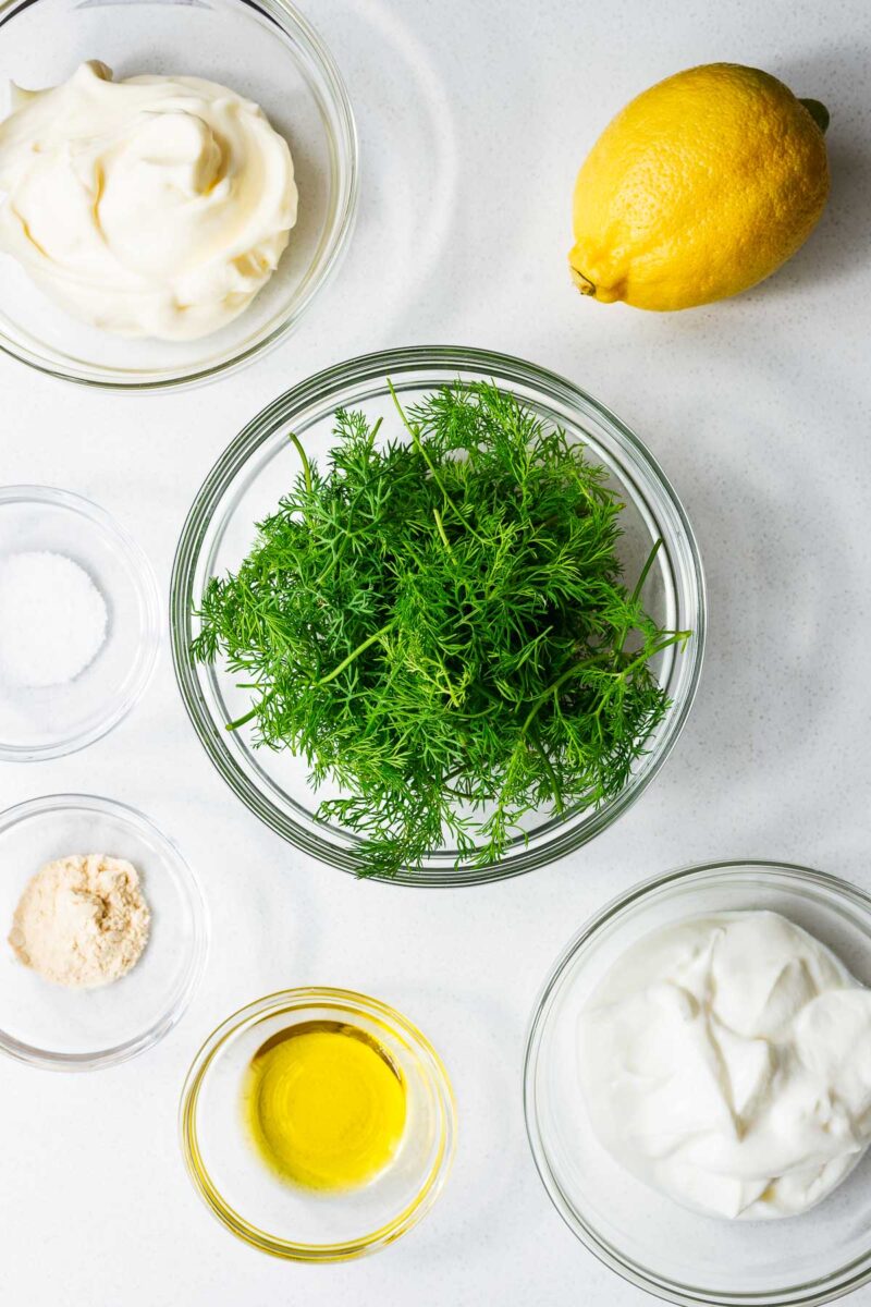 All the ingredients for an easy dill dressing arranged in glass bowls and viewed from above.