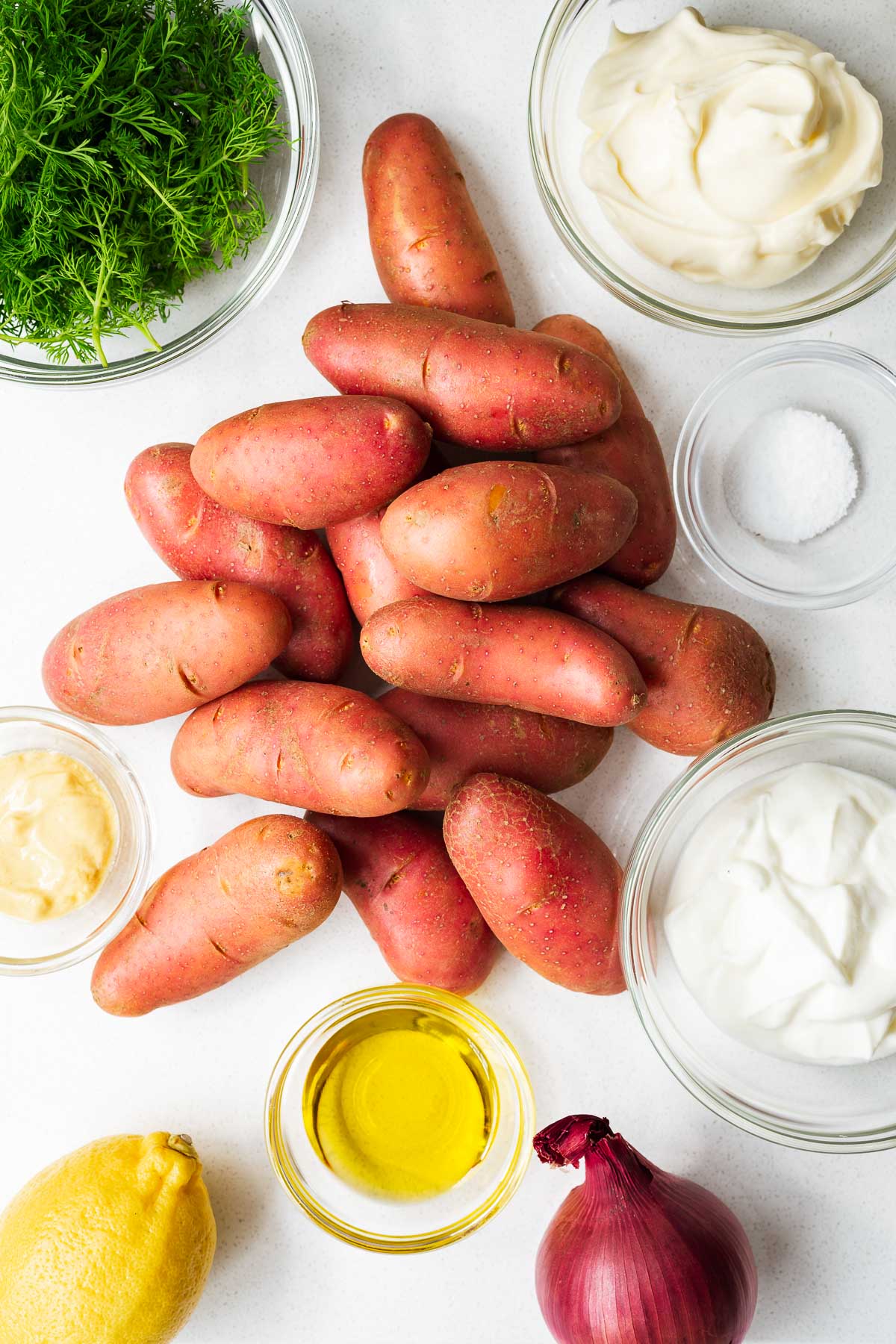 Ingredients for a red potato salad with dill and creamy yogurt dressing viewed from above.