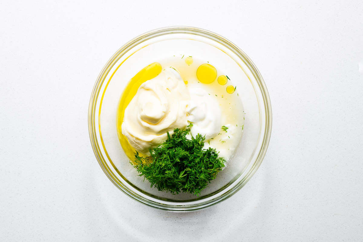Dill yogurt sauce ingredients combined in a glass bowl.