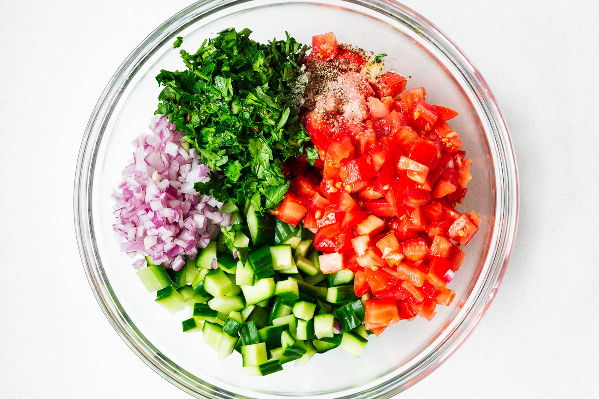 Cubed israeli salad ingredients in a mixing bowl.