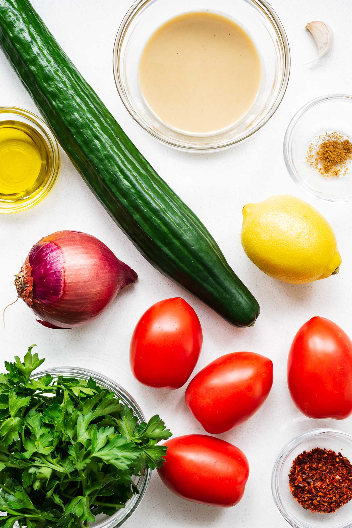 Tahini salad ingredients arranged on a kitchen counter viewed from above.