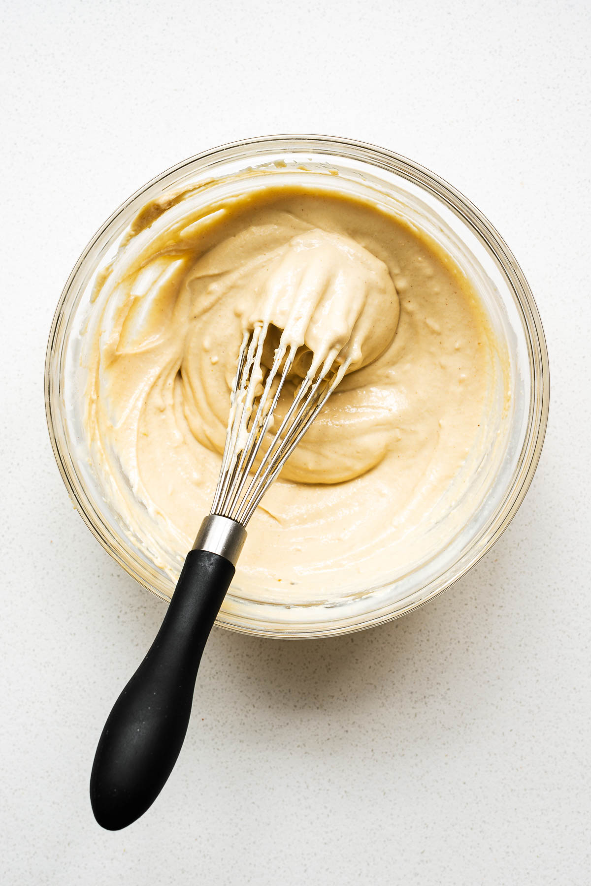 Easy tahini sauce for roasted cauliflower in a glass bowl with a whisk.