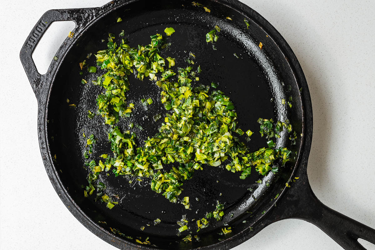 Finely chopped leeks cooked in a cast-iron skillet.